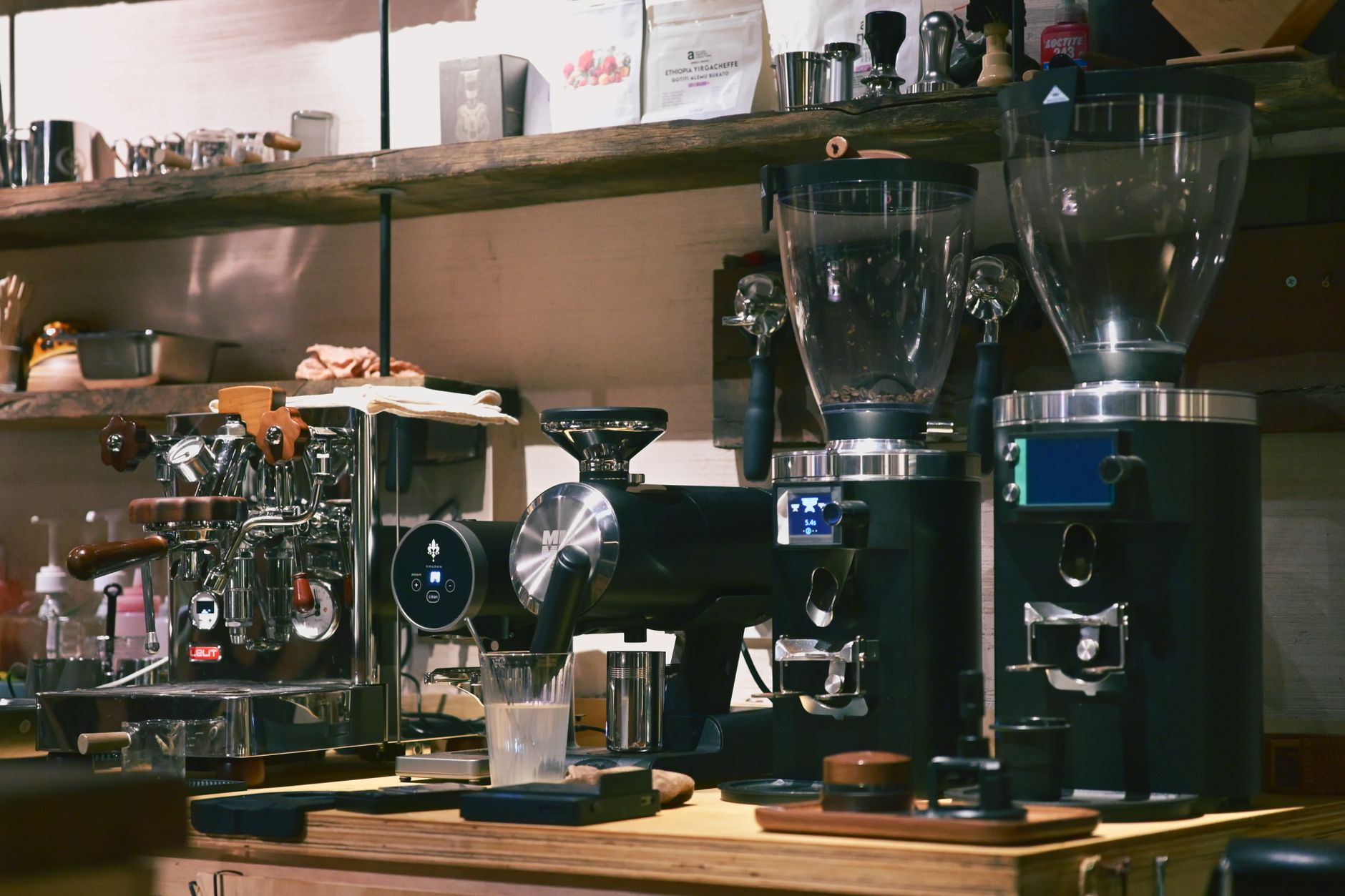 Espresso machine and grinders on a timber counter with shelves of coffee